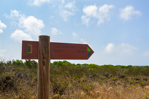 Signpost pointing the way on the Amoreira beach trail, with the colours of the Vicentina Route, a beautiful route that mixes sandy beaches, cliffs and vegetation. \nAljezur, Portugal.