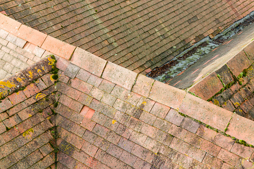 Aerial view of pitched tiled roof (rooves) on old English houses. Line of plain clay ridge tiles and roof valley, UK