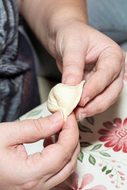 istock Hands soiled with flour hold a raw dumpling. Cooking homemade dumplings. Vertical shot 1295024389