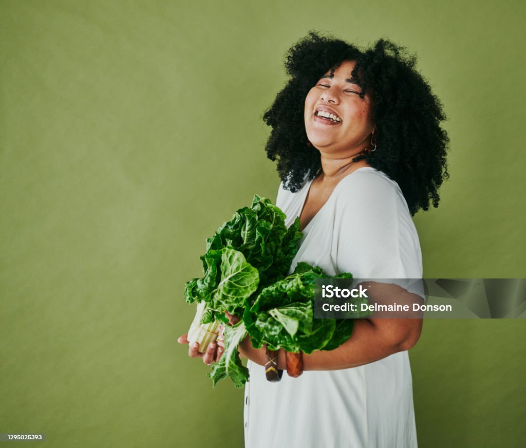 The better your food, the better your life Studio shot of a young woman holding a bunch of spinach against a green background Backgrounds Stock Photo