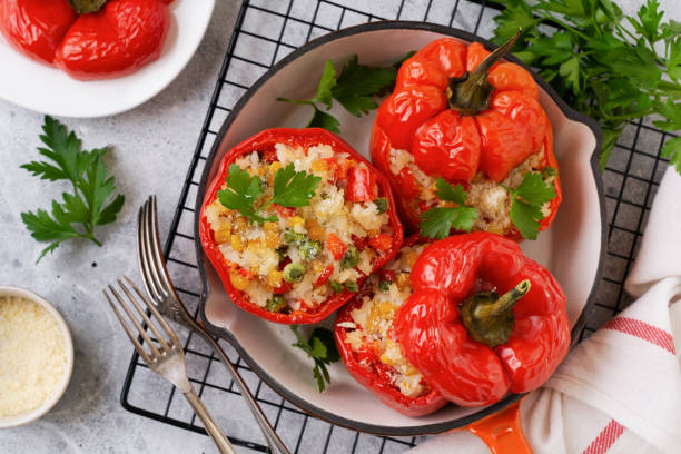 istock Red bell peppers stuffed with rice and vegetables on cast iron pan on gray concret background. 1295025710