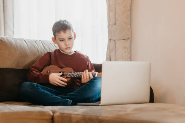 istock Boy Playing Guitar While Sitting On Sofa At Home 1295028445