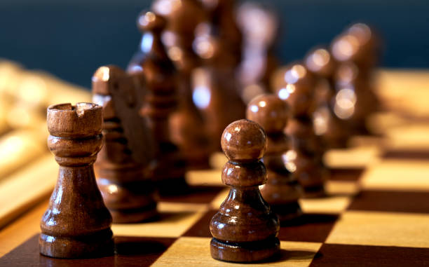 istock Black pieces on the chess board in the basic position at the beginning of a game, selective focus on the front rook and pawns. 1295030251