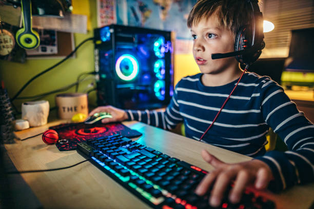 jeune garçon jouant des jeux sur un ordinateur à la maison, pendant la pandémie. - video game flash photos et images de collection