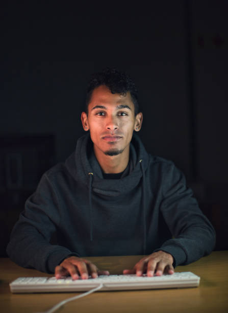istock Young man concentrates as he works late, illuminated by glowing computer screen 1295034477