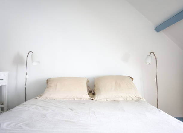 istock Bed and lamp in a white bedroom 1295034811
