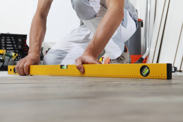 man worker hands installing timber laminate floor. Precise finishing using spirit level. Wooden floors house renovation.