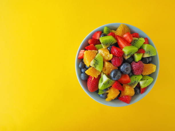 istock Fruit salad in a bowl on black background (kiwi, orange, strawberry, blueberry) 1295036077