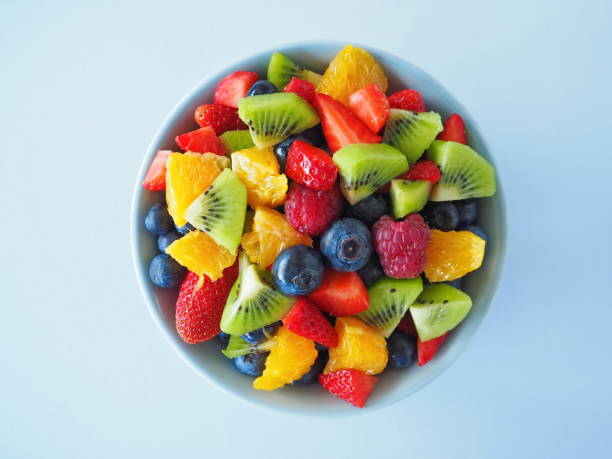 istock Fruit salad in a bowl on black background (kiwi, orange, strawberry, blueberry) 1295036084