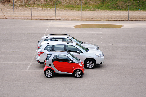 BAVARIA, GERMANY - AUGUST 11, 2014: Car parking. Small red car is standing next to large cars.