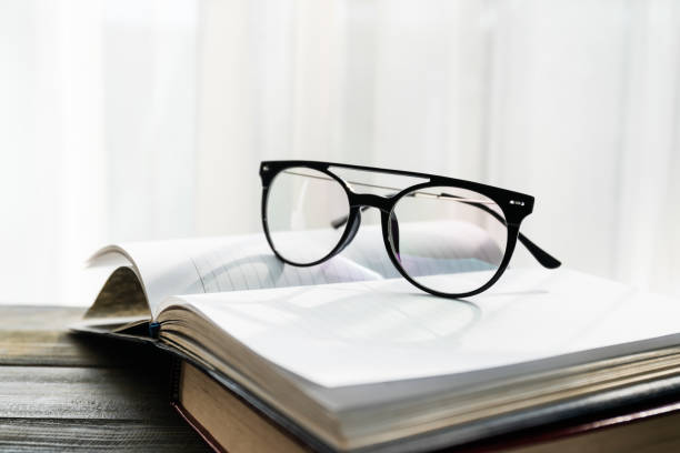 istock Reading glasses put on open book beside the window 1295038642