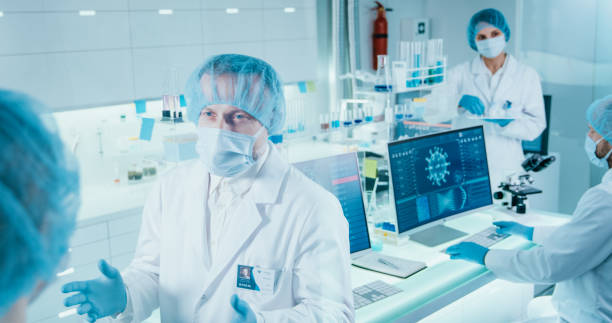 istock COVID-19 - diverse laboratory team working on coronavirus samples. Wearing protective workwear 1295039427