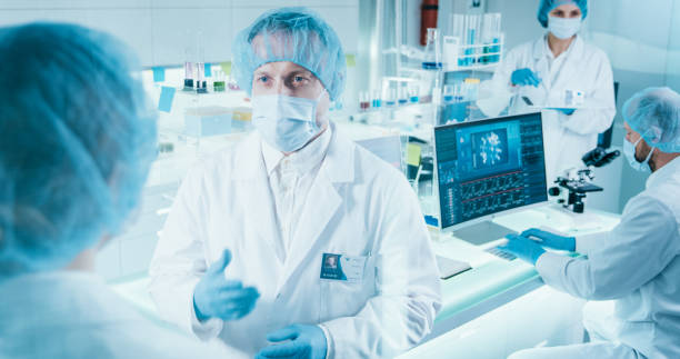 istock COVID-19 - diverse laboratory team working on coronavirus samples. Wearing protective workwear 1295039462
