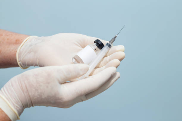 Vaccine and syringe in the hands of nurse. Goiania, Goias, Brazil - January 07, 2021: Photography done in studio. Nurse hands with gloves holding vaccine and syringe. vacina stock pictures, royalty-free photos & images
