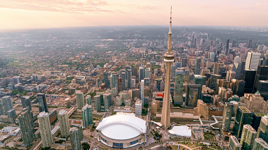 Aerial view of modern cityscape with CN Tower and Rogers Centre stadium at sunset, Toronto, Ontario, Canada.