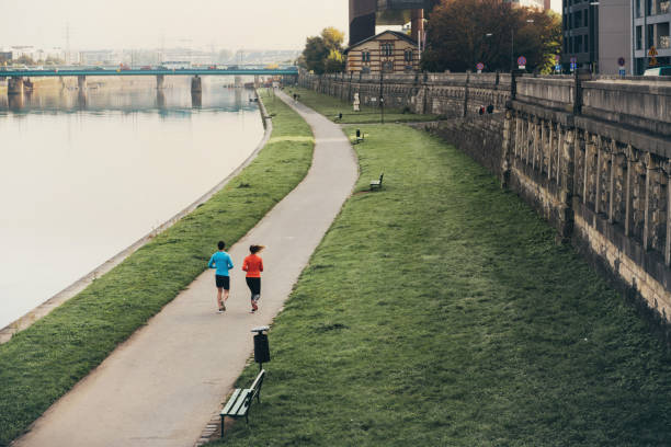 rear view on woman and man running at riverside in the morning
