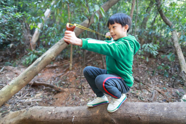istock young boy with slingshot shooting 1295044654