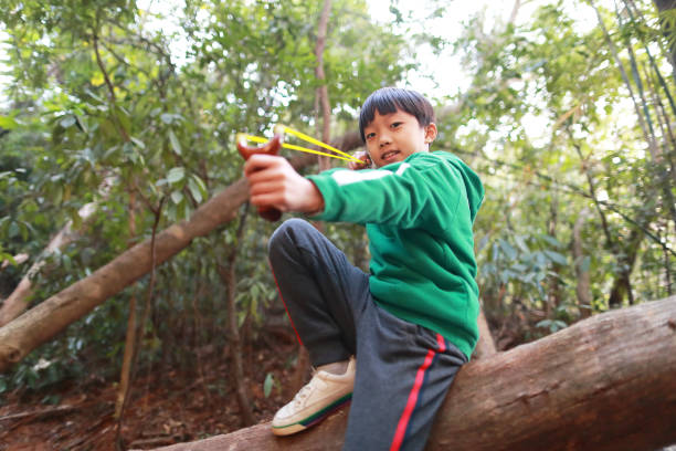 istock young boy with slingshot shooting 1295044674
