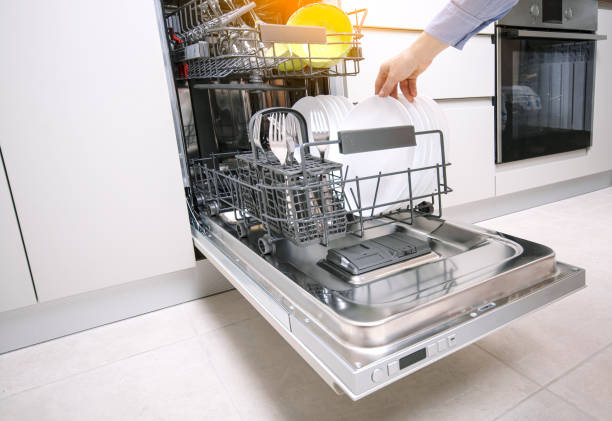 istock Integrated dishwaher machine loading. Female hand puts plates in dishwasher standing in a modern kitchen. 1295045583