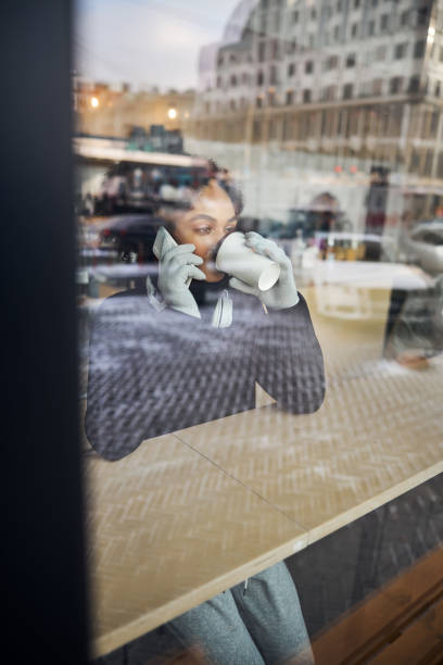 istock Female cafe customer drinking while talking on a cellphone 1295048042