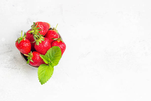istock Fresh ripe juicy strawberries with mint leaves on a grey stone background. Fruit concept. Minimalism. Top view. Copy space. 1295048241