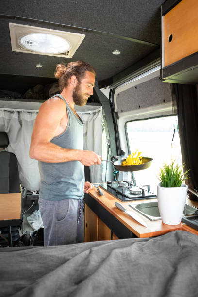 istock Man cooking food inside his camper van 1295048401