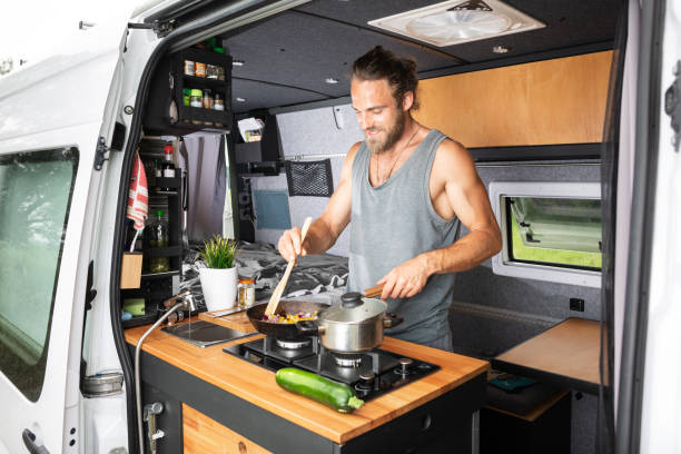 istock Man cooking on a stove inside his camper van 1295048447
