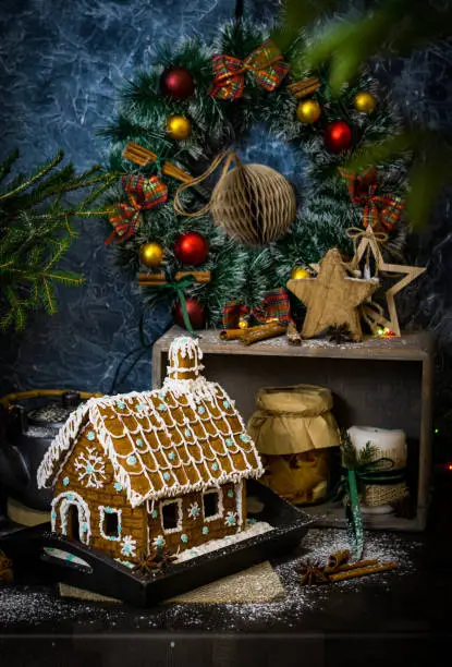 Festive Christmas styling of homemade gingerbread house decorated with sugar snowflakes