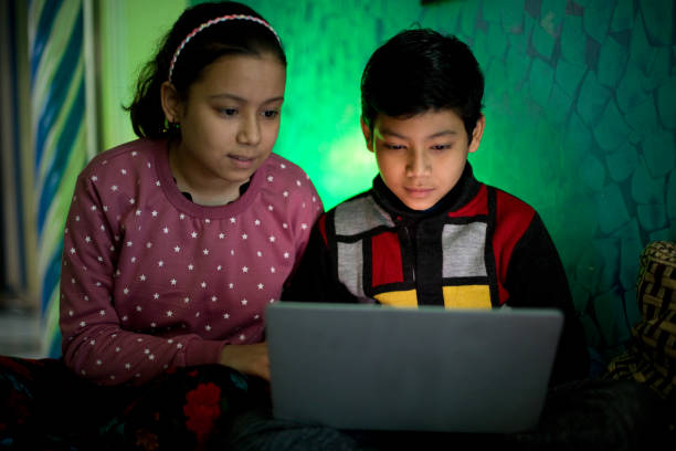 istock Brother and sister having fun using laptop at home 1295056175