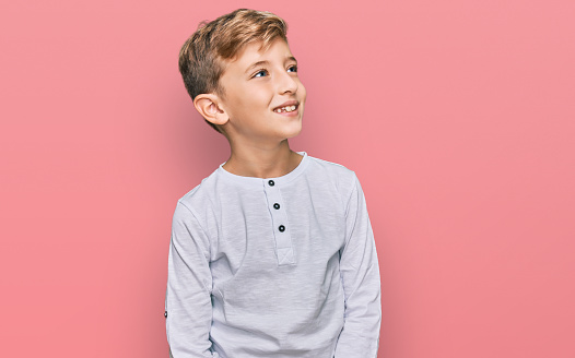 Little caucasian boy kid wearing casual clothes looking away to side with smile on face, natural expression. laughing confident.