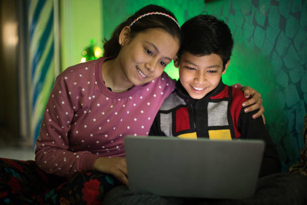 istock Brother and sister having fun using laptop at home 1295057168