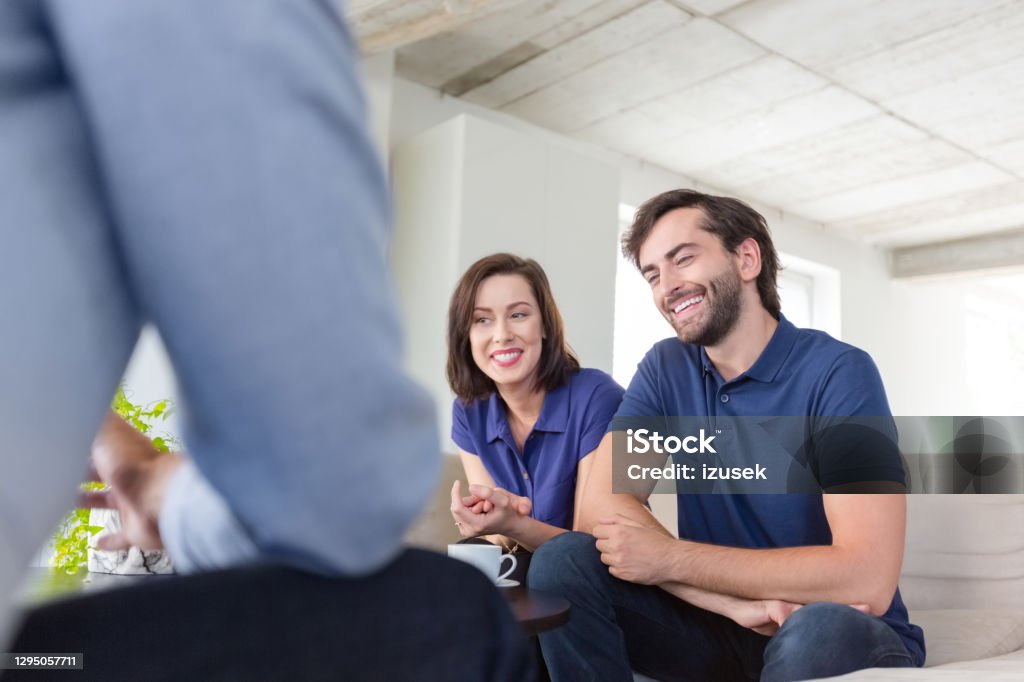 Couple discussing problems with psychotherapist Mid adult couple discussing problems with psychotherapist sitting in living room. They are in meeting at home. Financial Advisor Stock Photo