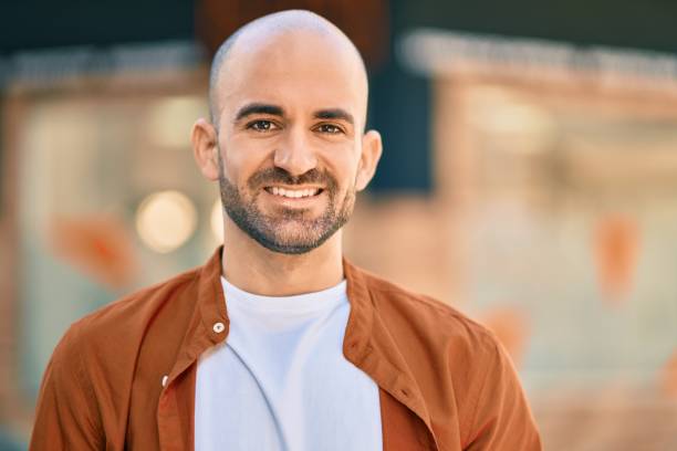 istock Young hispanic bald man smiling happy standing at the city. 1295062507