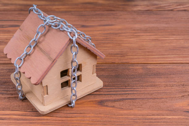 istock House in chains on wood background. Protection, security, alarm concept 1295063902