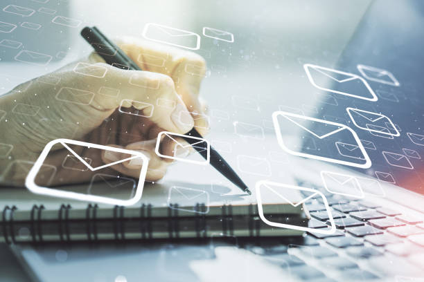 istock Double exposure of postal envelopes hologram with hand writing in notebook on background with laptop. Electronic mail and spam concept 1295067959