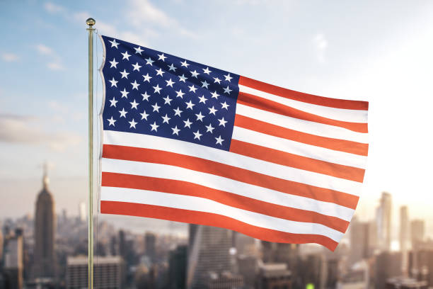 istock USA flag on blurry cityscape background at sunset 1295068022