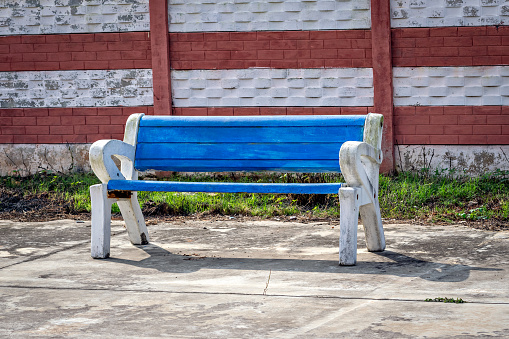 Bright blue colored sitting bench with white handrest on a railway platform in India.