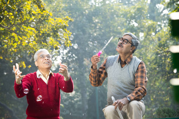 istock Two senior men enjoying blowing bubbles at park 1295069208