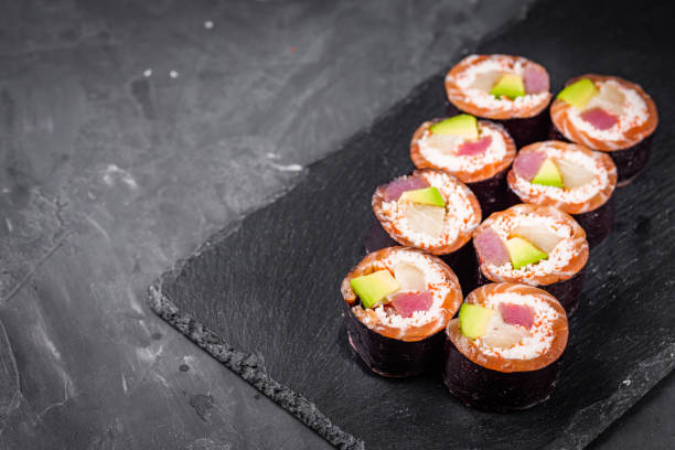 istock appetizing sushi roll with tuna salmon escolar crab and avocado on a black stone plate 1295069604