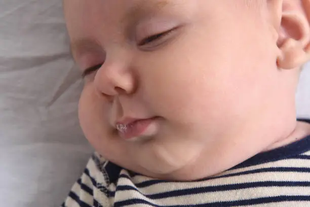 Photo of relaxed baby with drool in the mouth, side view