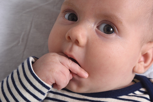 Close-up of the baby who puts his hand in his mouth to suck his finger