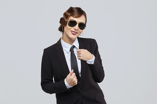 attractive woman with a retro hairstyle and a smile on her face. posing in a men's suit and sunglasses