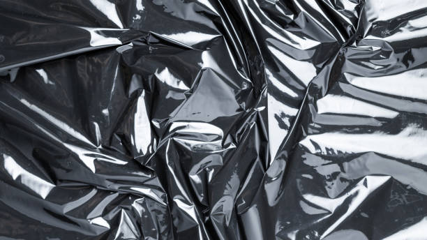 istock Plastic black background. Wrap transparent dark cellophane. Black shiny film bag pattern. Real texture of polyethylene foil. 1295071008