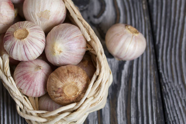 istock Garlic in a wicker basket. Close-up shot. On black pine boards. 1295072472