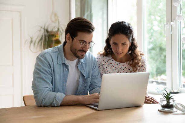 istock Young family using laptop together, sitting at table in kitchen 1295072603