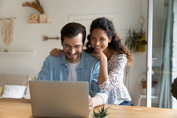 istock Happy young man and woman hugging, using laptop together 1295072663