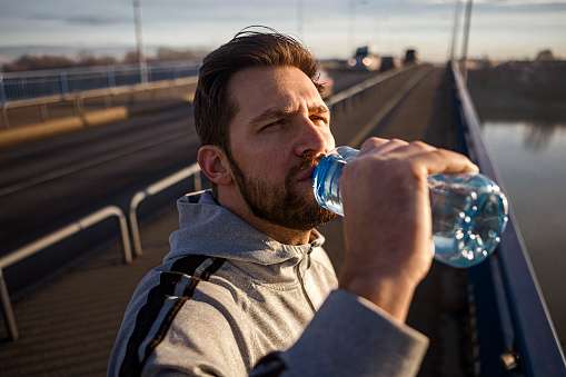 Young man hydrating after jogging