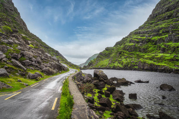 route sinueuse étroite fonctionnant le long du lac dans gap de dunloe - winding road sunlight field cultivated land photos et images de collection