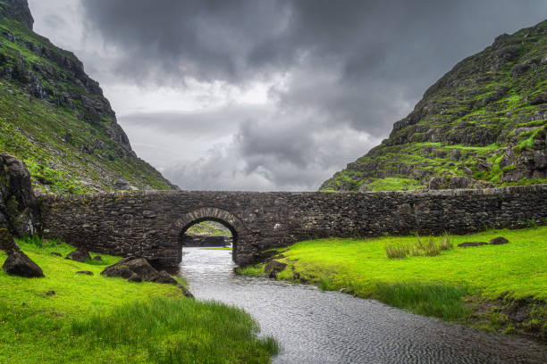 маленький каменный мост желаний над извилистым потоком в гэп данло - macgillicuddys reeks стоковые фото и изображения