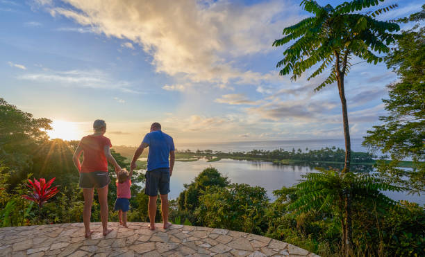 Father, Mother & Daughter Watching the Sunrise Over a Lagoon and the Pacific in Corcovado National Park on the Osa Peninsula in Costa Rica stock photo